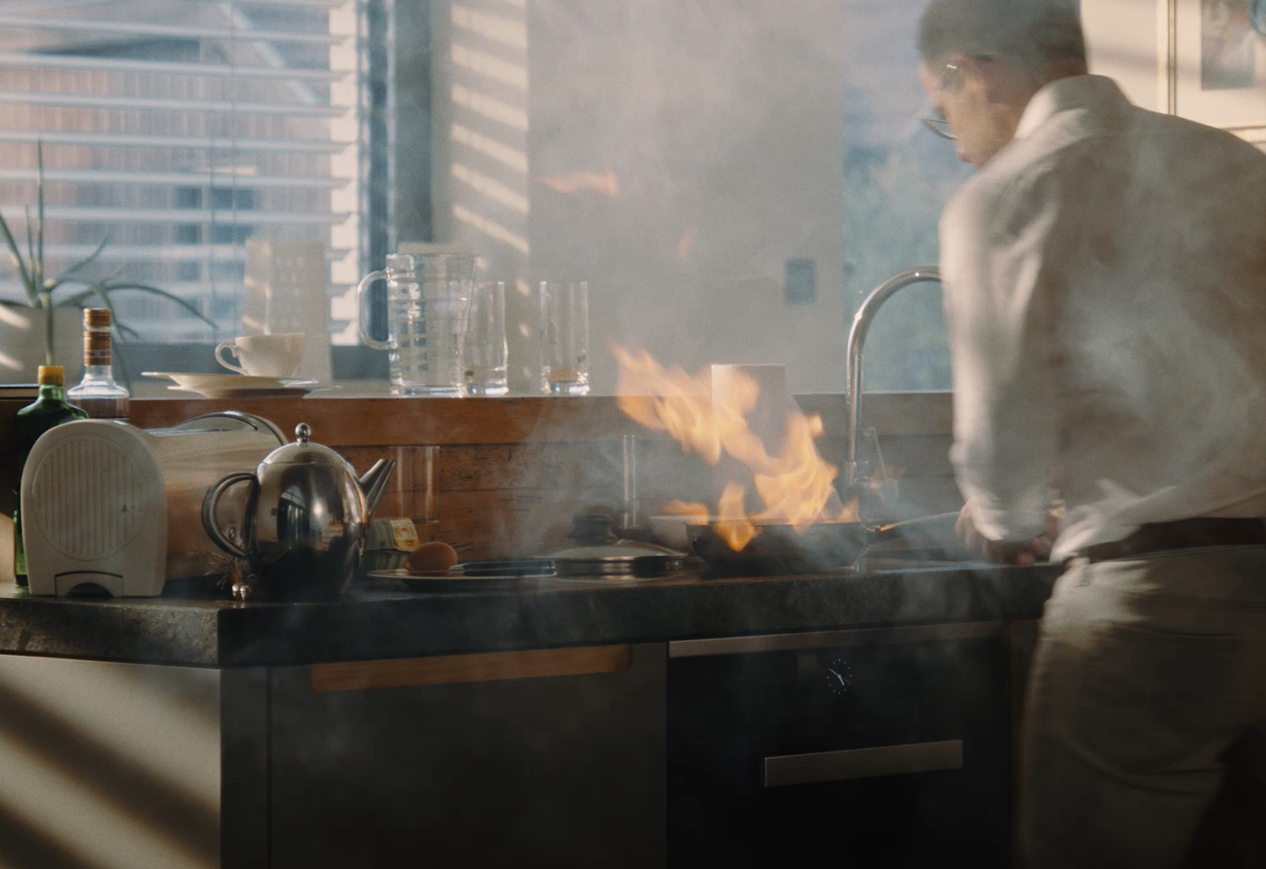 Screenshot aus dem Video wo ein Mann etwas kochen will, jedoch die Pfanne Feuer fängt.