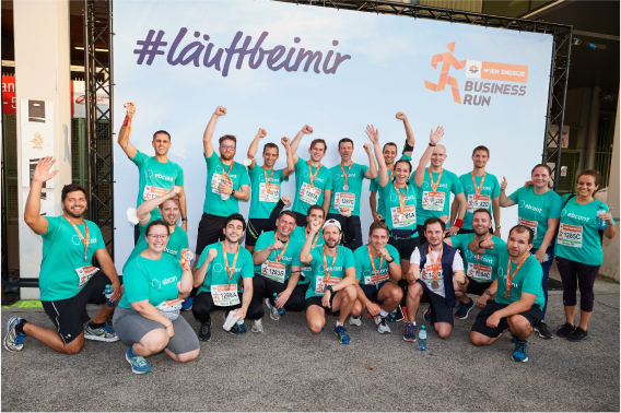 Eine Gruppe von etwa 20 EBCONT Kolleg:innen, gekleidet in passenden türkisfarbenen EBCONT-T-Shirts, posiert gemeinsam nach der Teilnahme an einem Business-Run-Event. Sie lächeln und halten Medaillen.