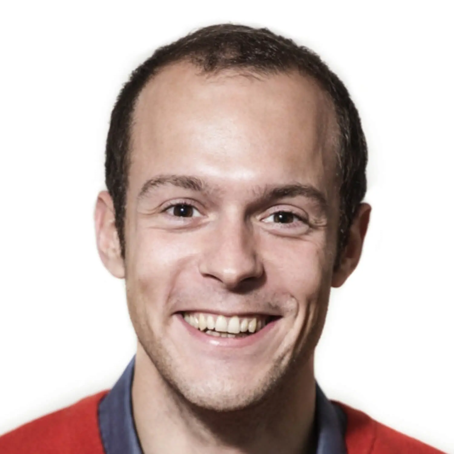 Junger Mann mit kurzen dunklen Haaren, lächelt freundlich in die Kamera. Er trägt ein rotes Oberteil über einem dunkelblauen Hemd, der Hintergrund ist weiß und neutral gehalten.