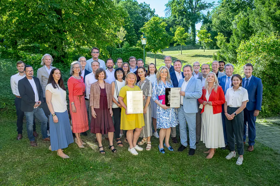 Mehrere Menschen stehen zusammen in einem Park mit grünen Wiesen und Bäumen
