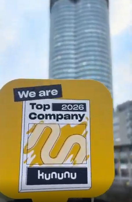 a sign with the kununu logo and the text “We are Top Company 2026,” with the Millennium Tower in the background